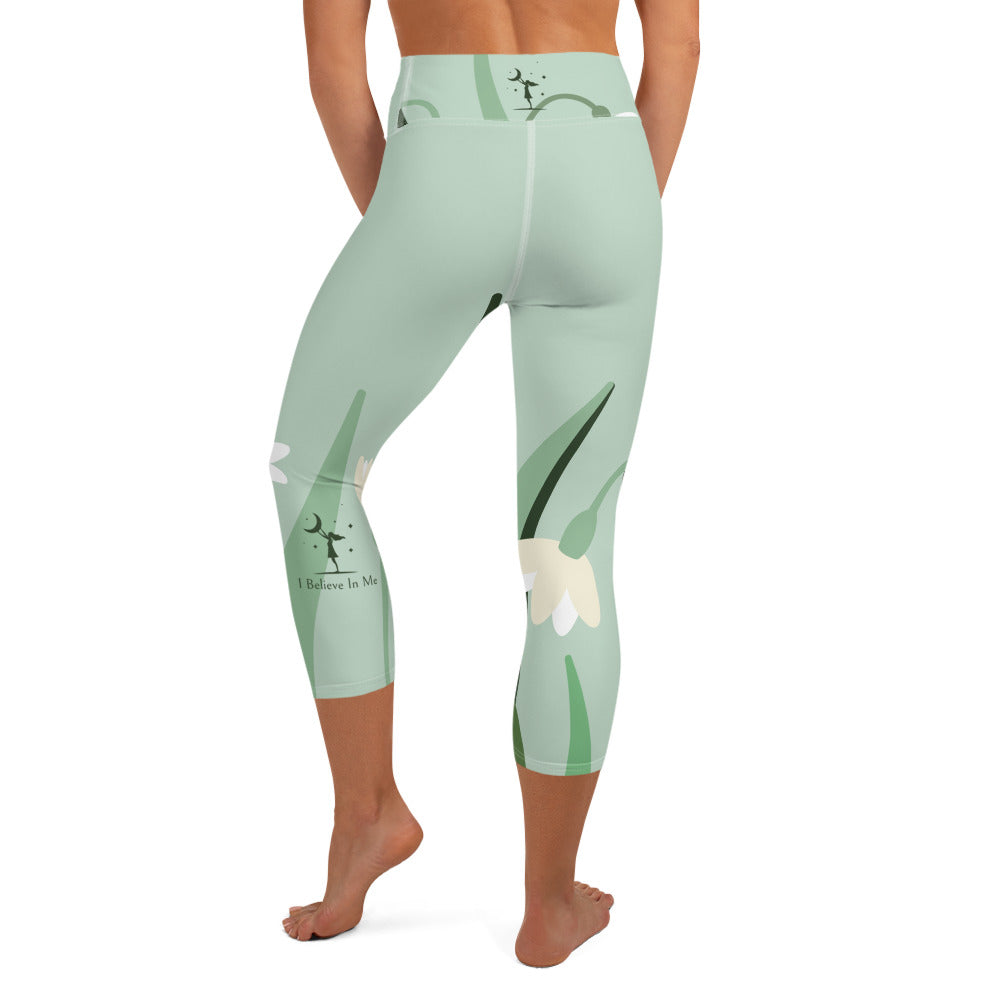 view of a barefoot woman wearing mint colored capri length yoga pant with green and white flowers