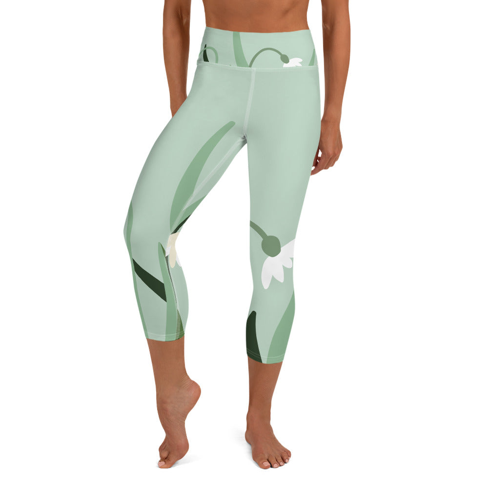 front view of a barefoot woman wearing mint colored capri length yoga pant with green and white flowers