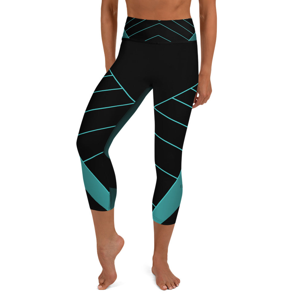 front view of a barefoot woman wearing black and teal capri length yoga pants